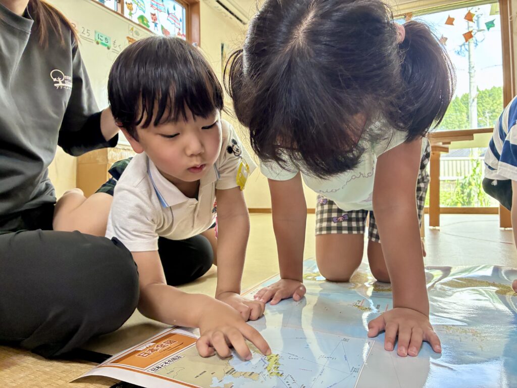 鹿児島市・日置市からこどもたちが通う児童発達支援事業所(療育支援事業所)アナベルキッズで、 地図を囲んで場所を指さしている。
