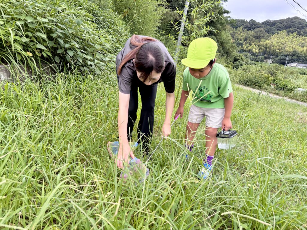 アナベルキッズでお友達やスタッフと一緒に草の中の虫を探すこどもたち