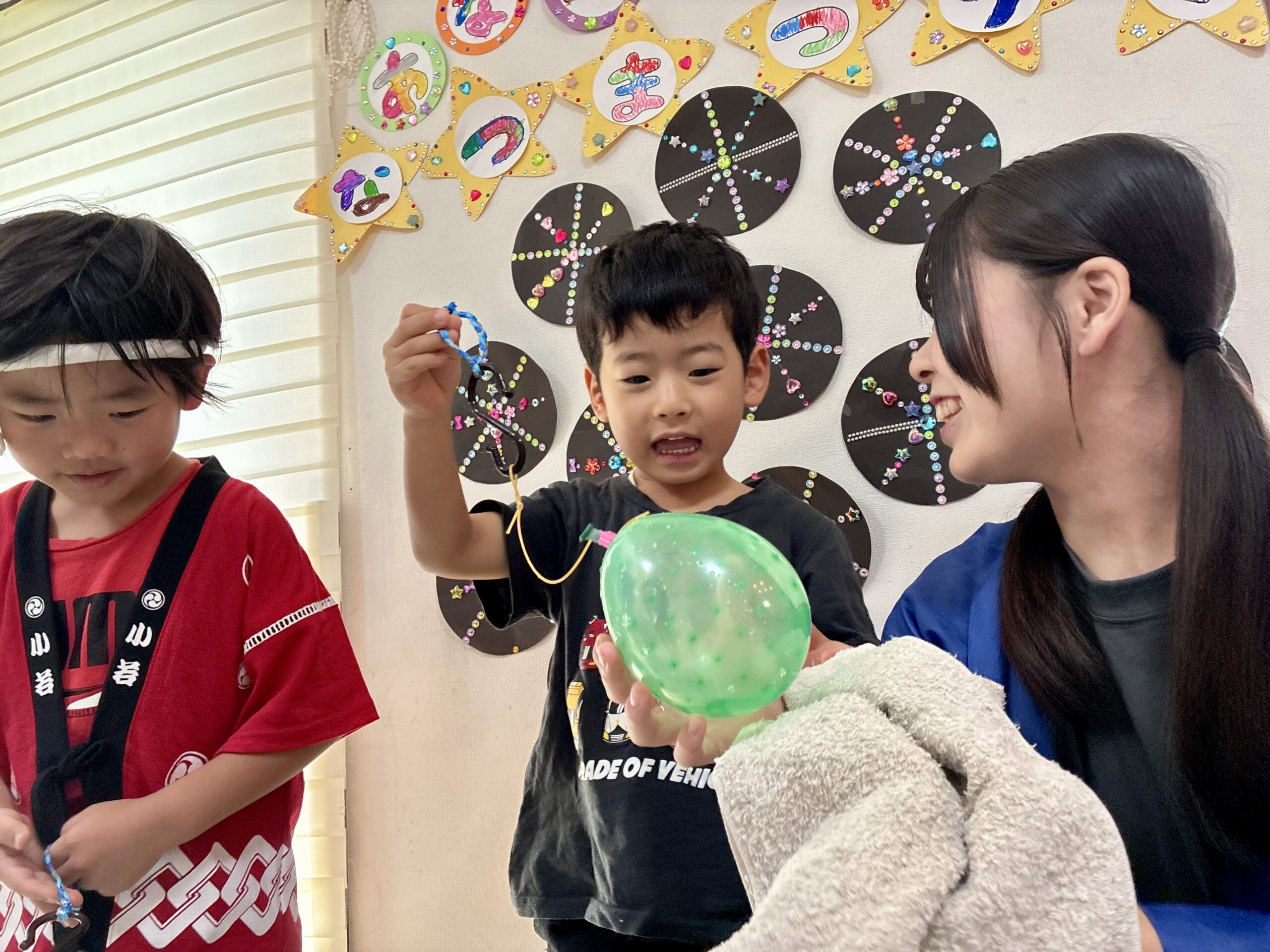 緑色の水ヨーヨーをつり上げる子どもと水ヨーヨーを手に持つ青い法被姿の大人
