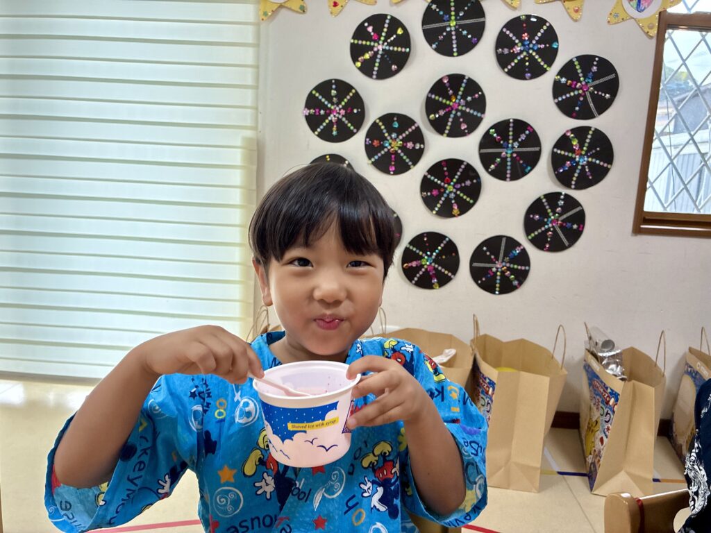 青い柄の甚平姿でカップ入りのかき氷を持つ子ども