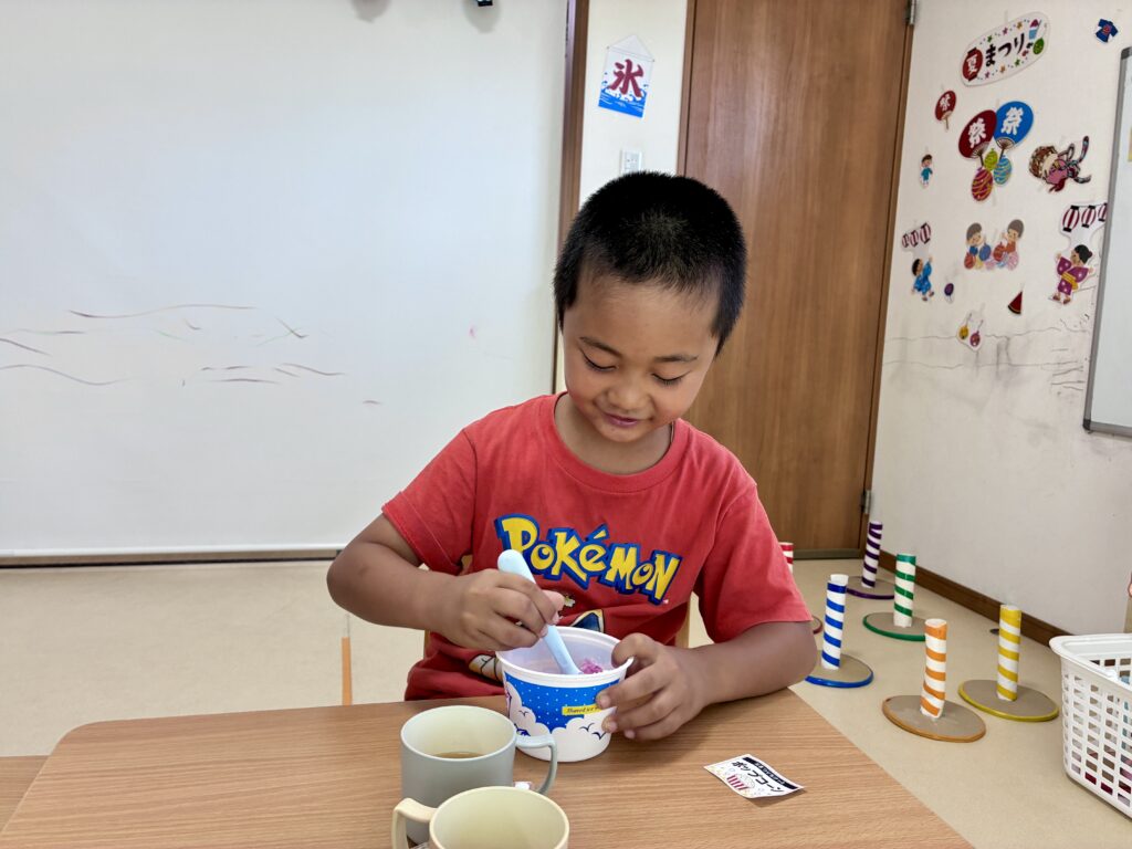 カップのかき氷をスプーンで混ぜるこども