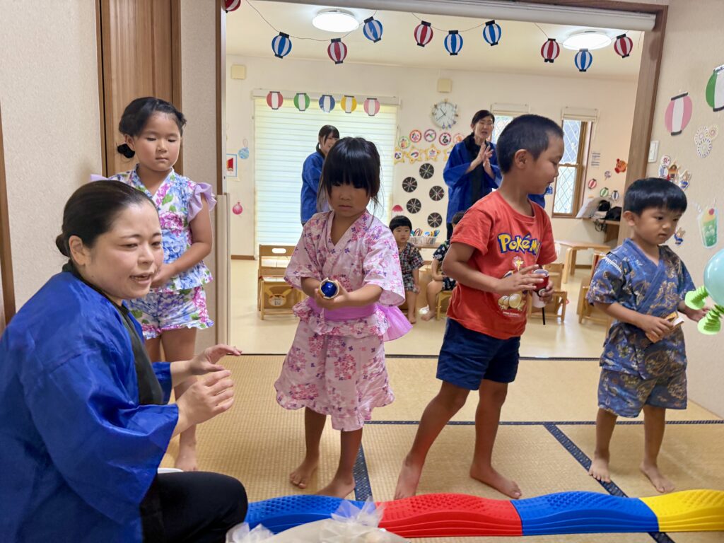 夏祭り会場に立つ浴衣・甚平姿のこどもたちとスタッフ
