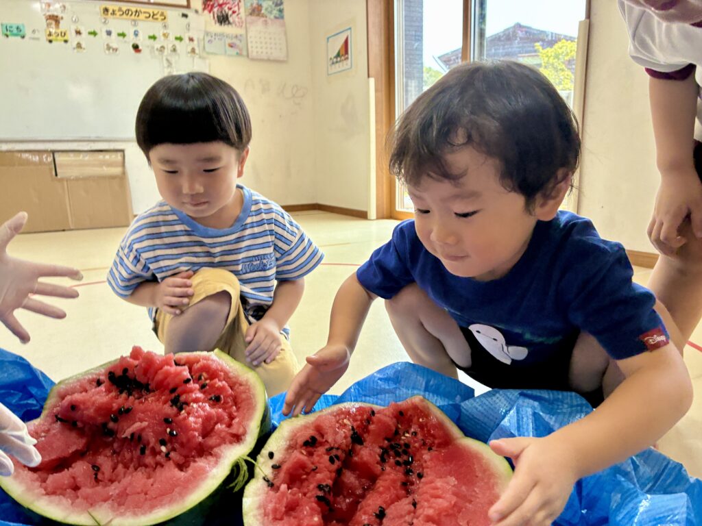 割れた大きなスイカを囲むこどもたち