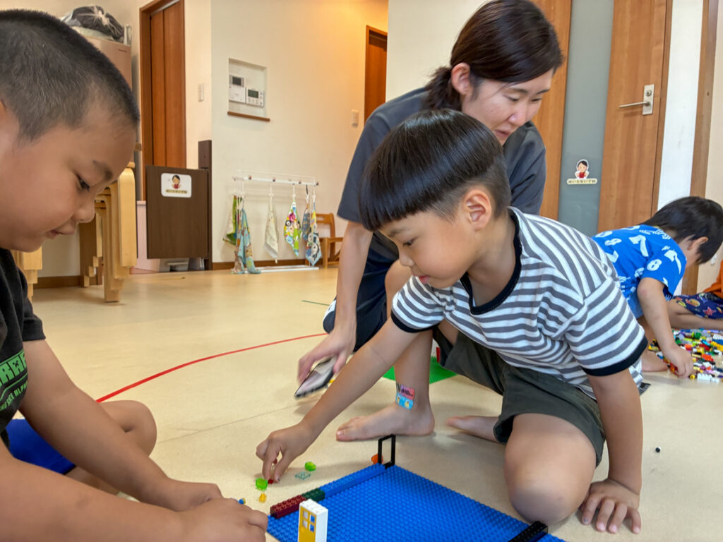 友だちと青い土台にブロックを置く様子