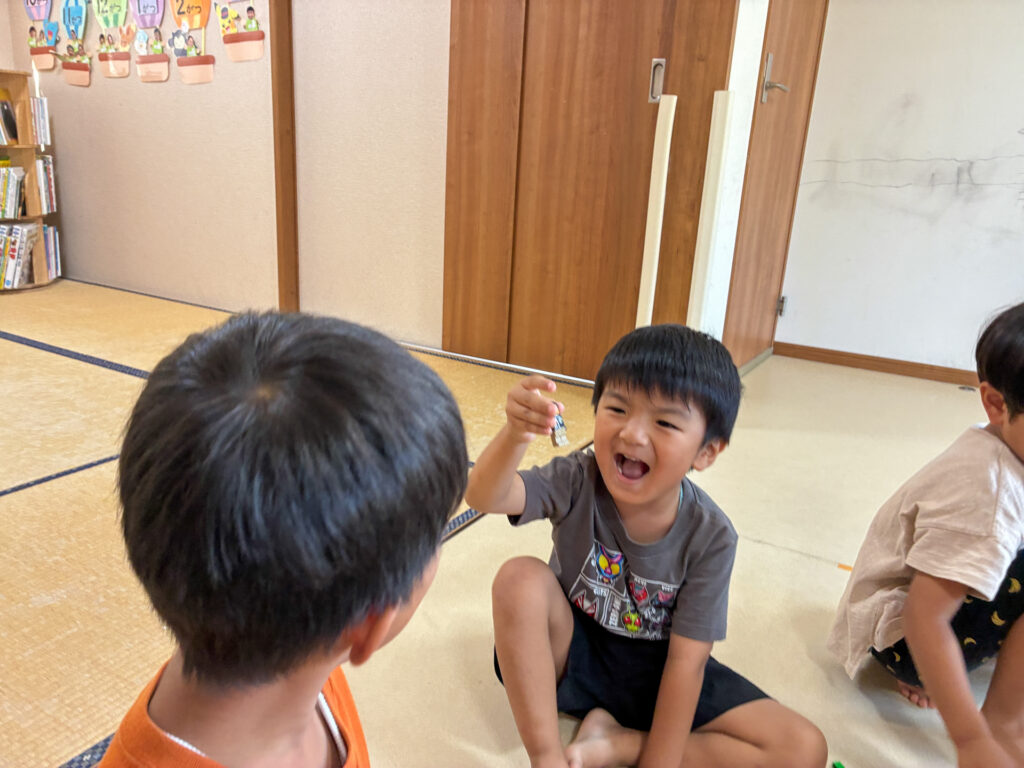 小さなブロックを掲げて友だちに見せる笑顔