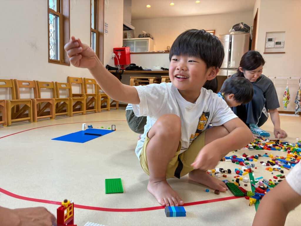 組み合わせたブロックを差し出して見せる笑顔
