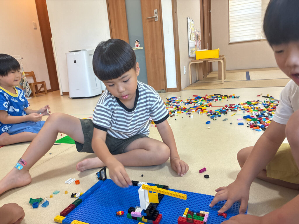 青い土台の上の作品にブロックを加える様子