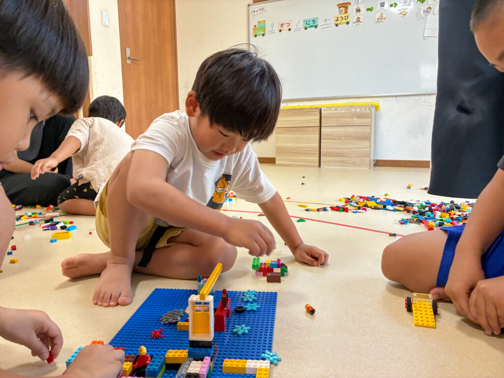友だちと並んで建物の形を組み立てる様子