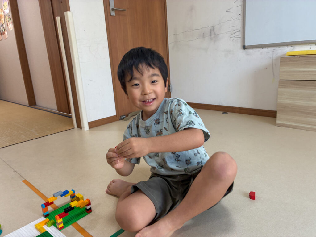 組み立てたブロックのそばで見せる笑顔