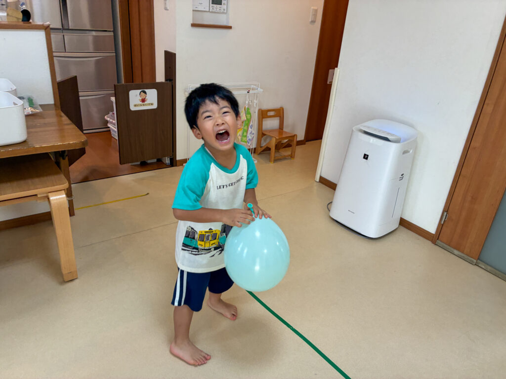風船を手にして大きな笑顔を見せる様子