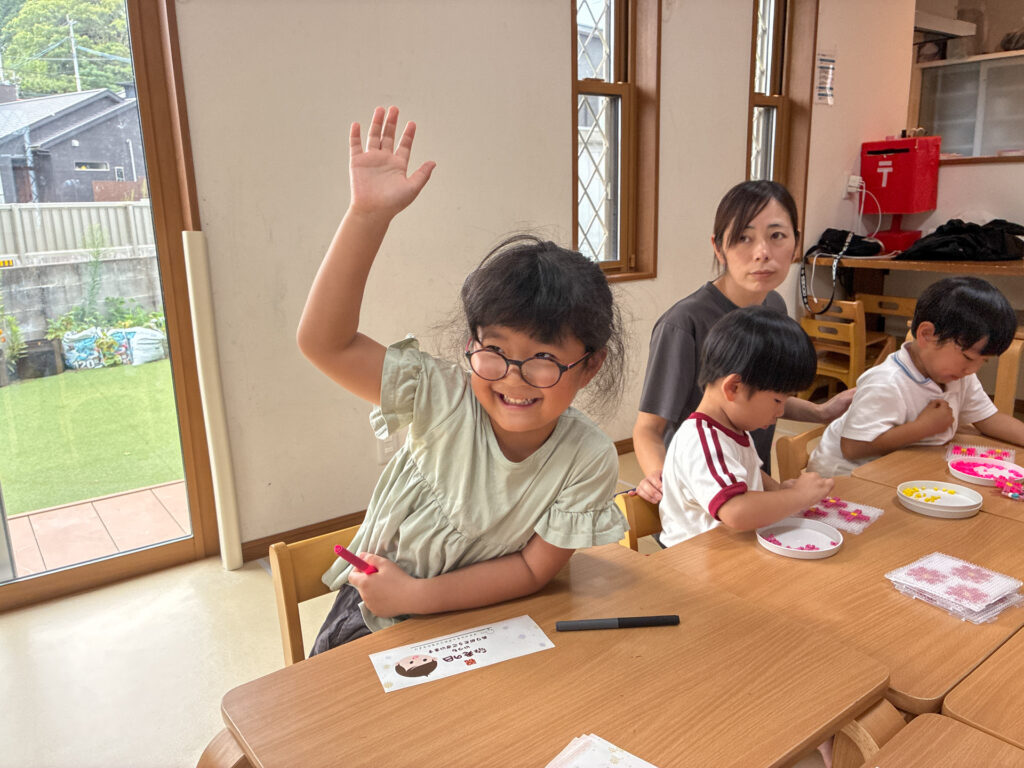 カードを前に手を挙げて笑う様子
