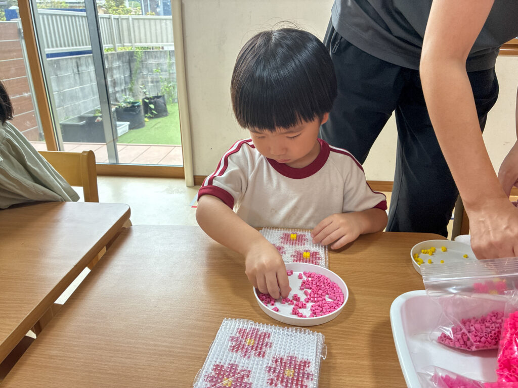 ピンク色のビーズを小さな台に並べる様子