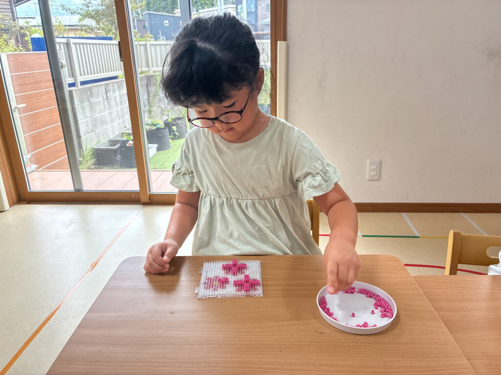 ビーズを選んで花の飾りを作る様子