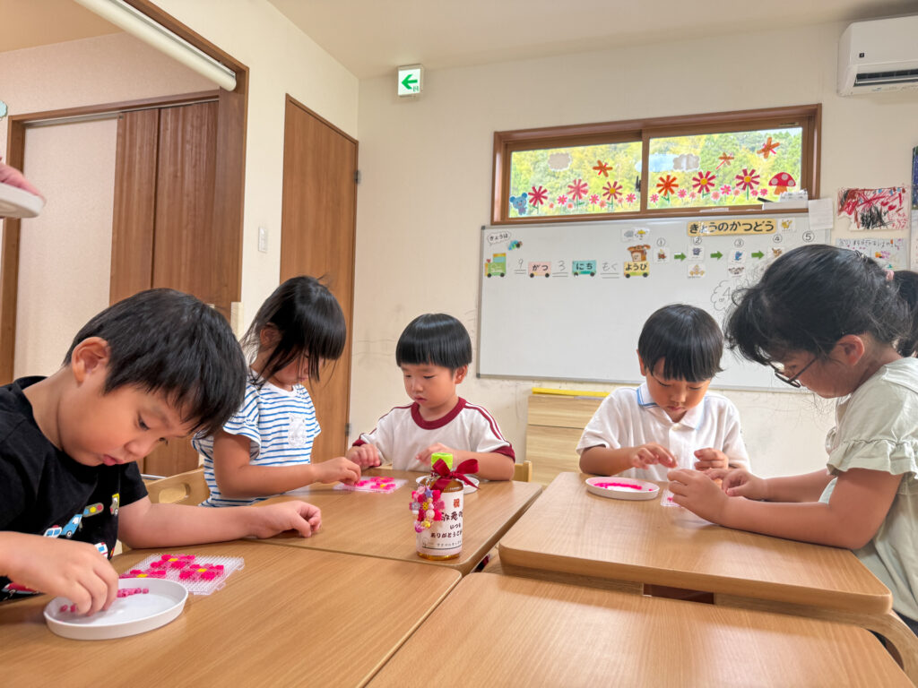こどもたちが机を囲んでビーズを並べる様子