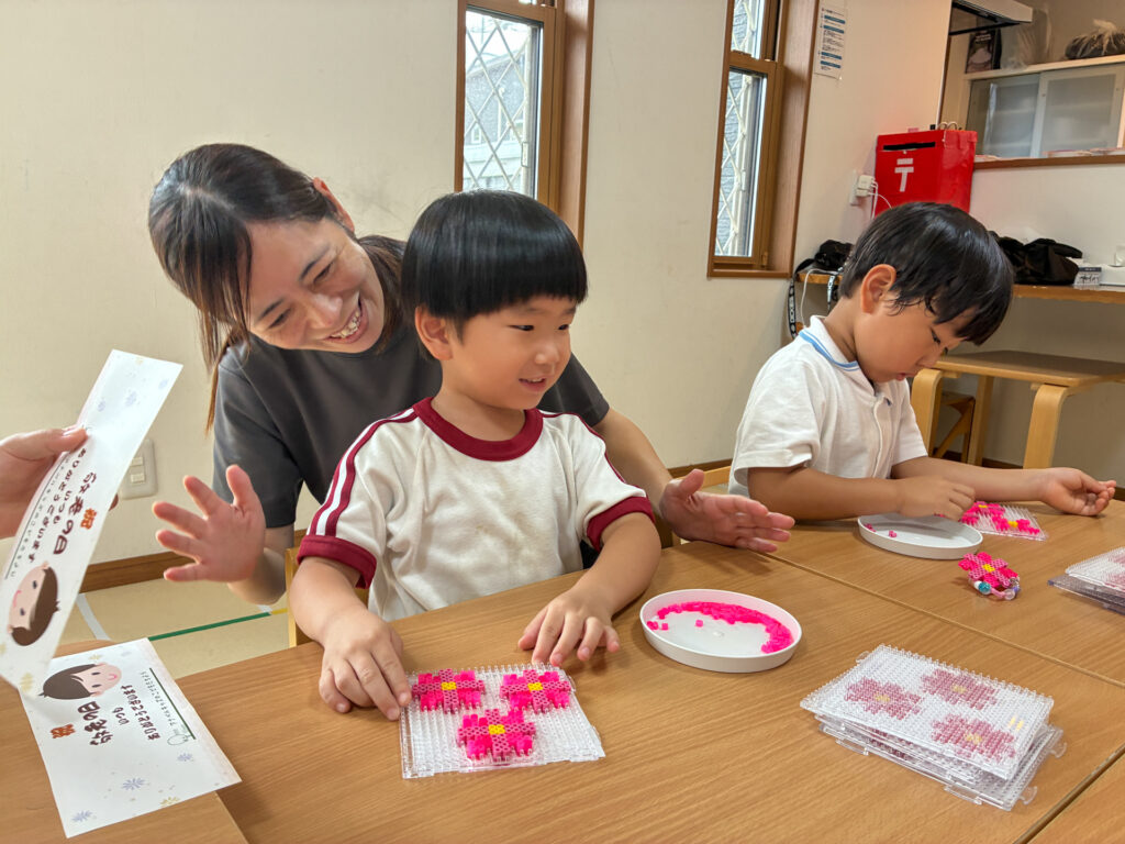 ビーズの花を前にスタッフと笑顔を見せる様子