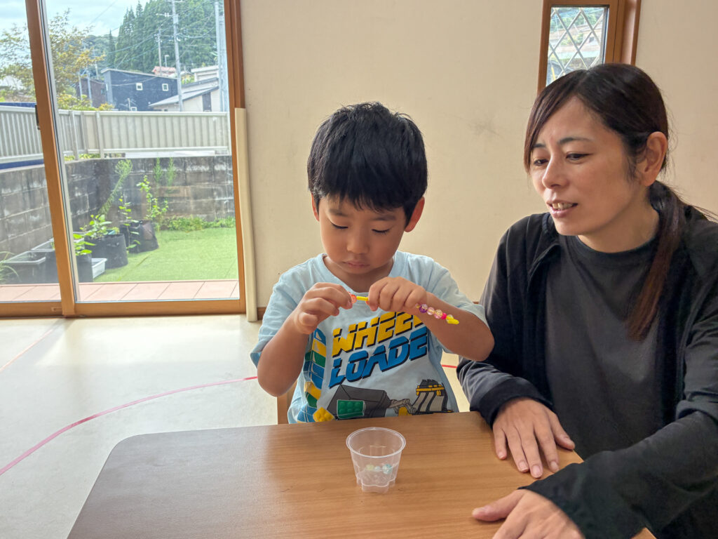 スタッフのそばでビーズを通す様子