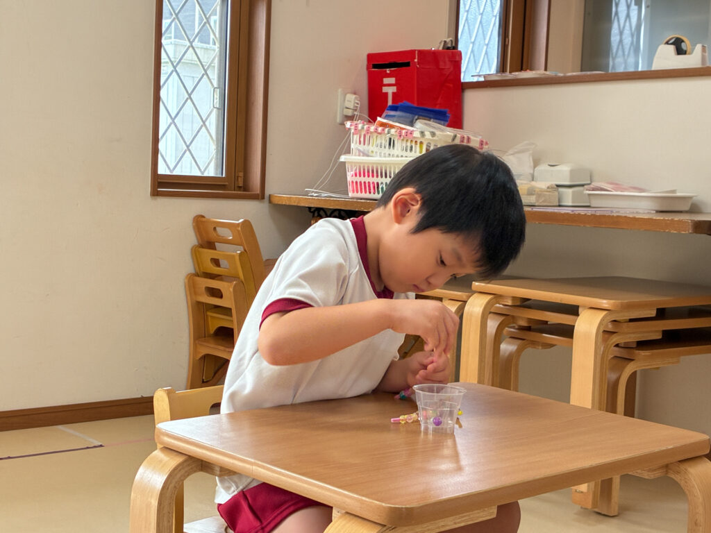 カップの中のビーズに指を伸ばす様子