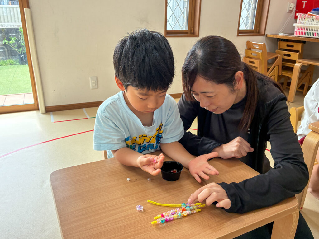 スタッフとできあがったビーズの飾りを並べる様子