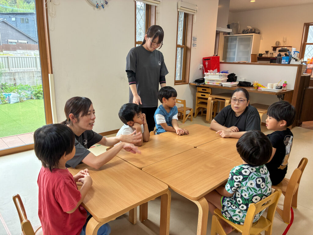 机を囲んでスタッフと話をするこどもたち