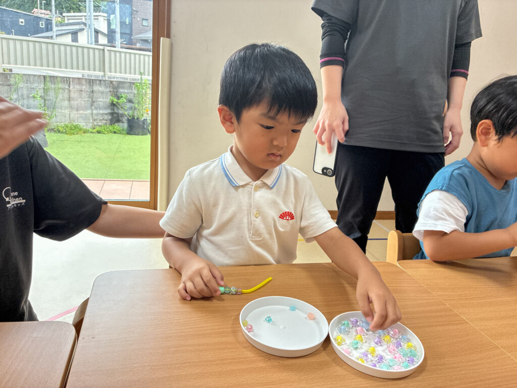 皿に手を伸ばしてビーズを選ぶ様子