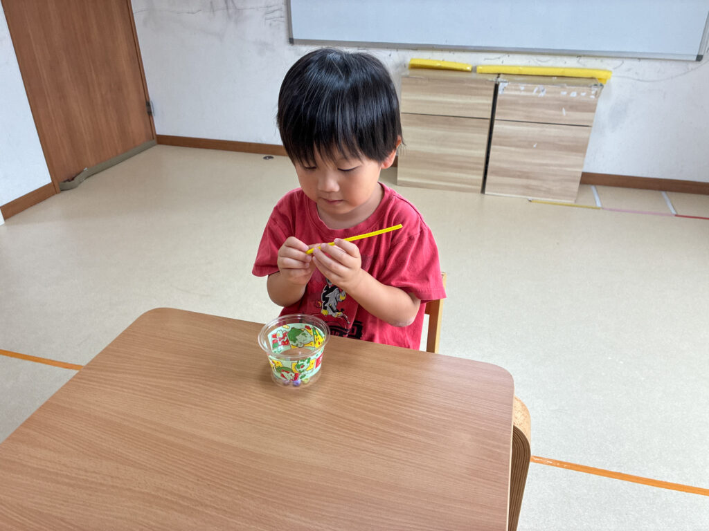 黄色いモールとビーズを両手で持つ様子