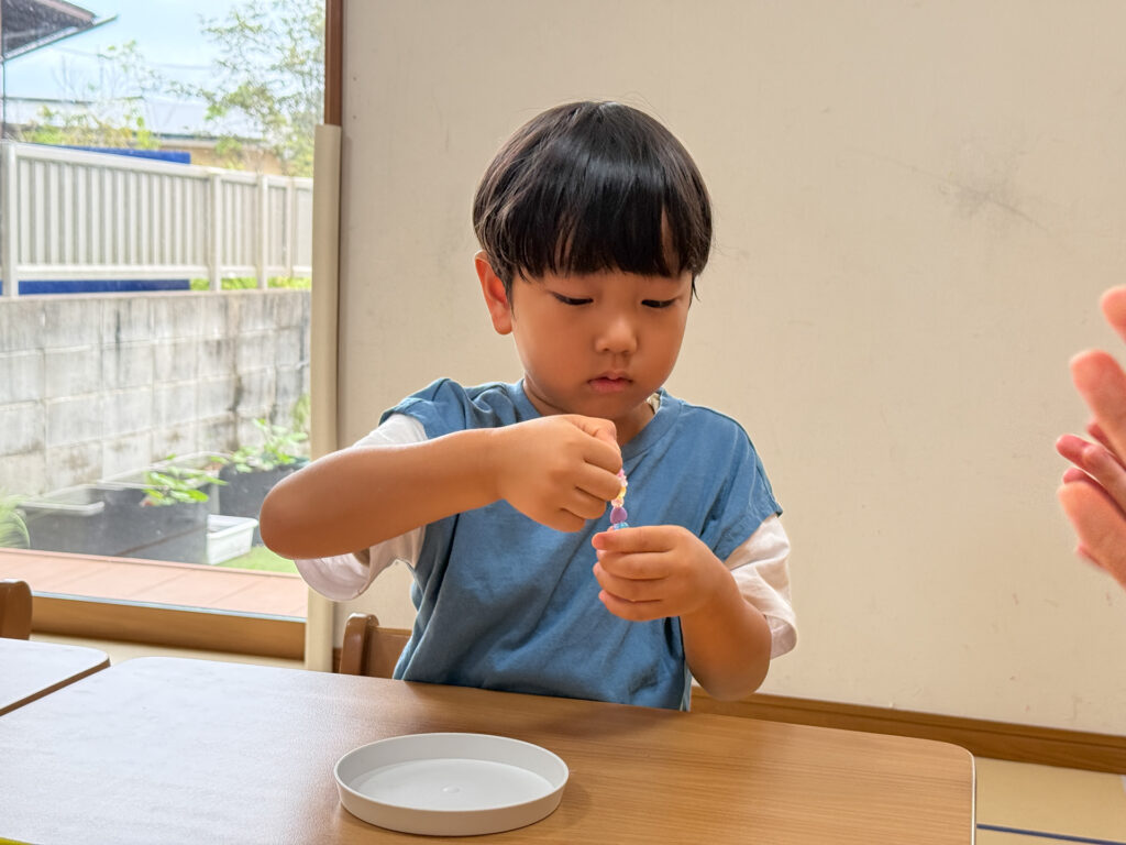 指先を見ながらビーズを通す様子