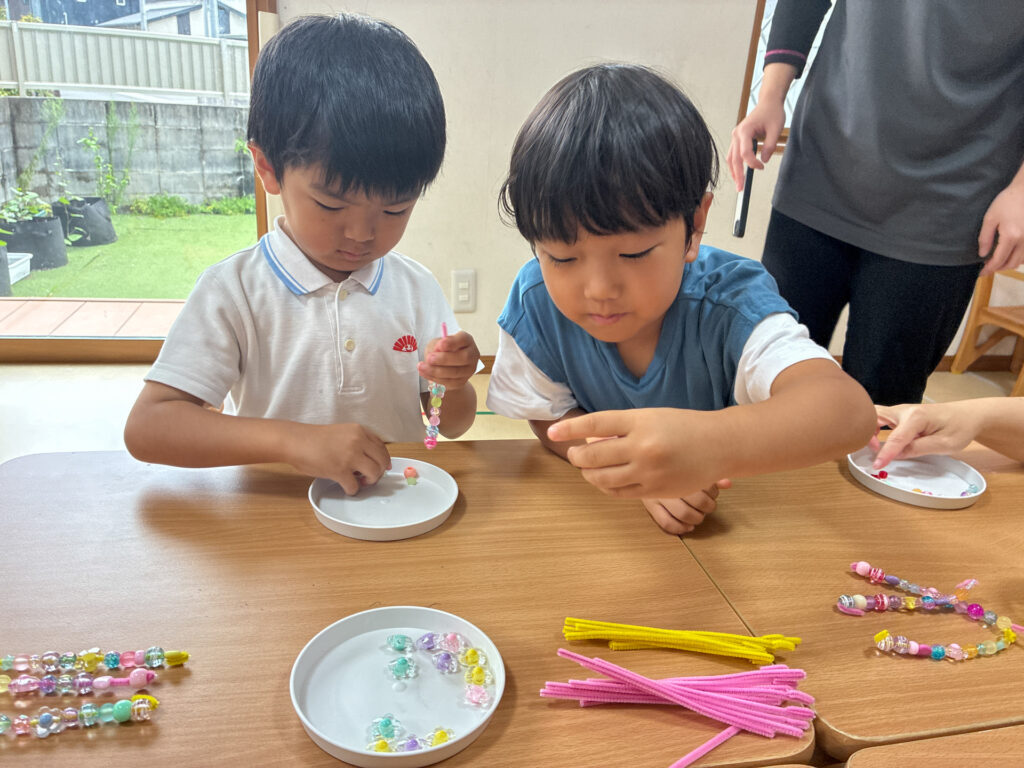 隣に並んでビーズを扱うこどもたち