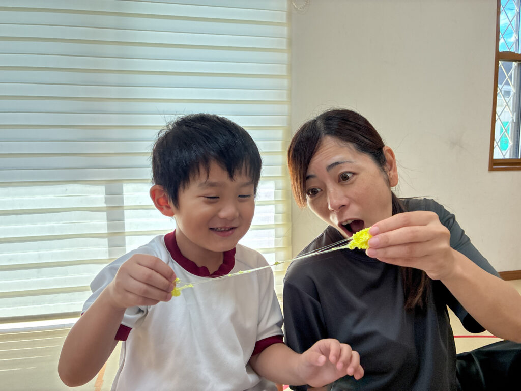 黄色い粘土を伸ばしてスタッフと見る様子