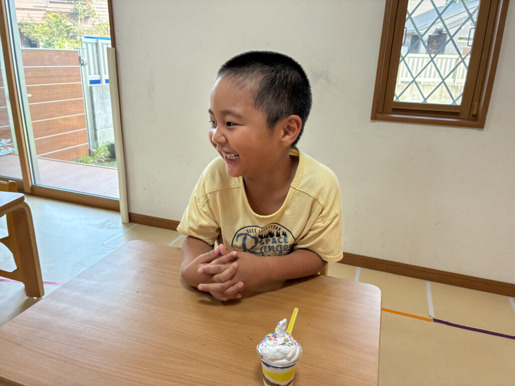 机の上のパフェを前に笑顔を見せる様子