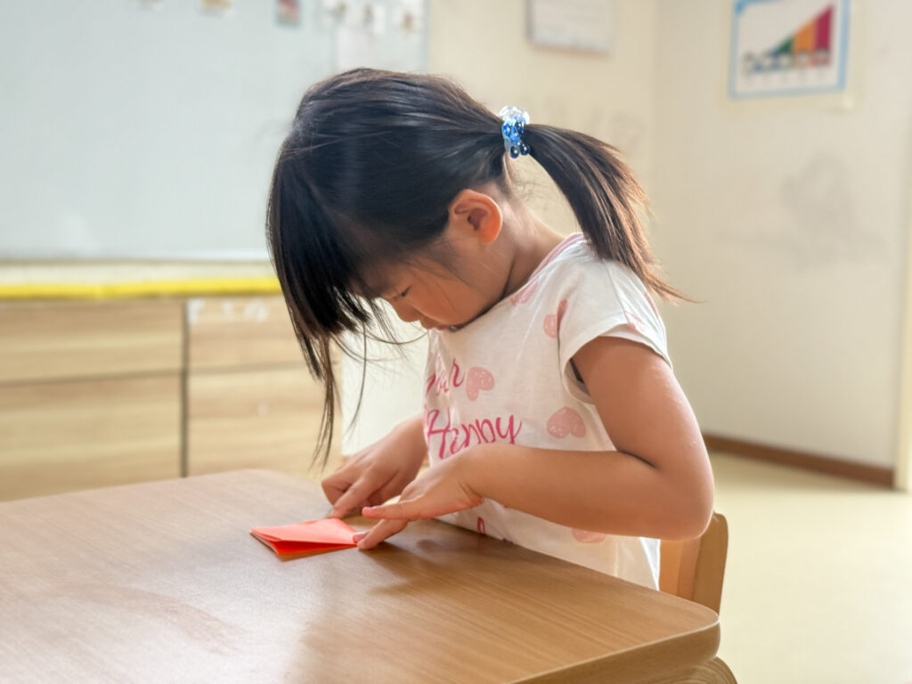 指先で折り紙を押さえて折る様子