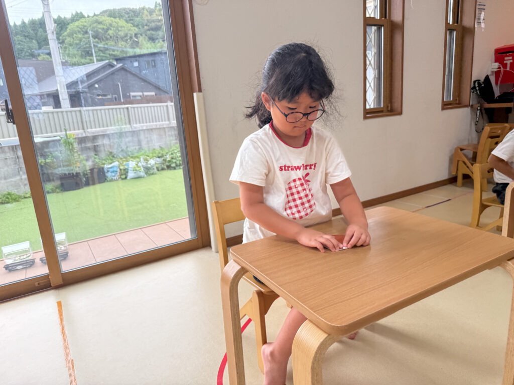 机に向かって折り紙を折る様子