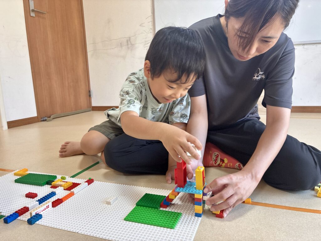 スタッフと一緒にブロックを組み立てる様子