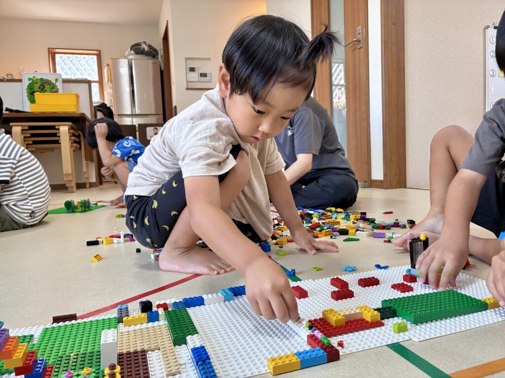 床に座ってそれぞれの場所でブロックに取り組むお友達たち
