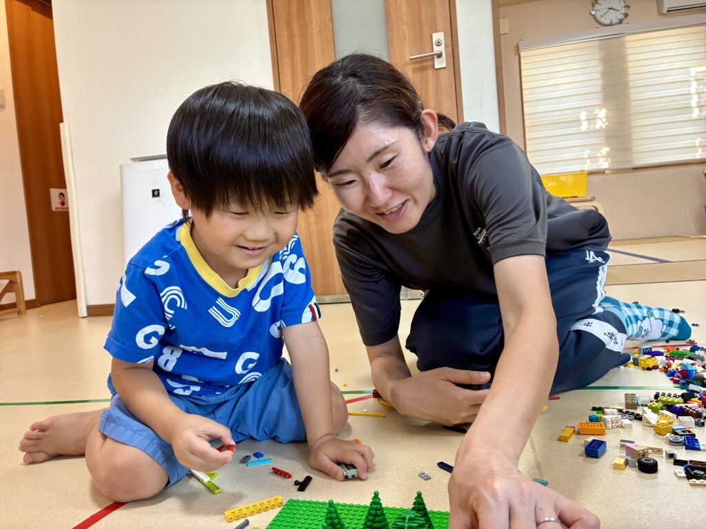 作品を囲んで一緒に取り組む数人のお友達とスタッフ
