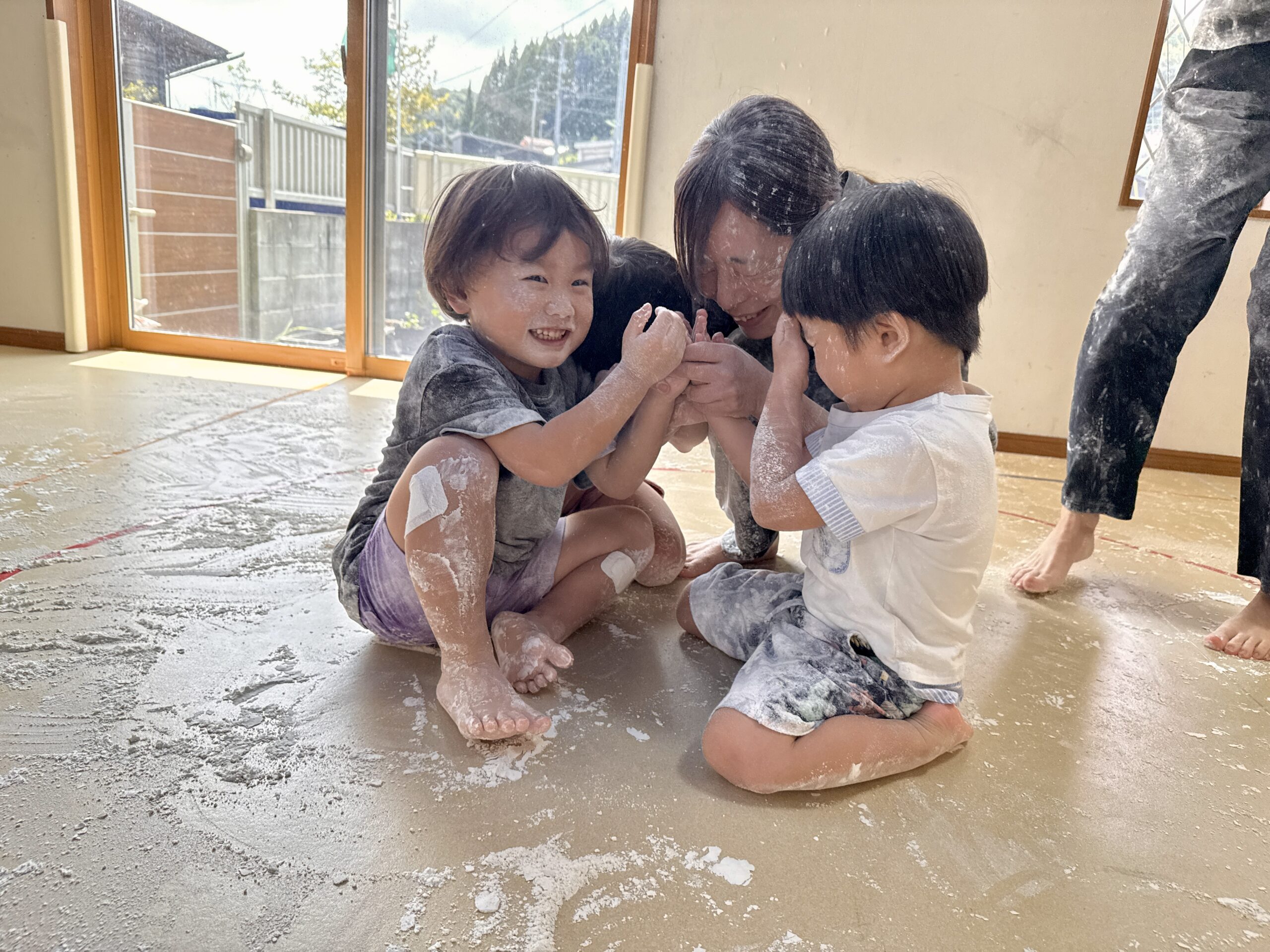 床にすわって小麦粉の上で過ごす子どもたち