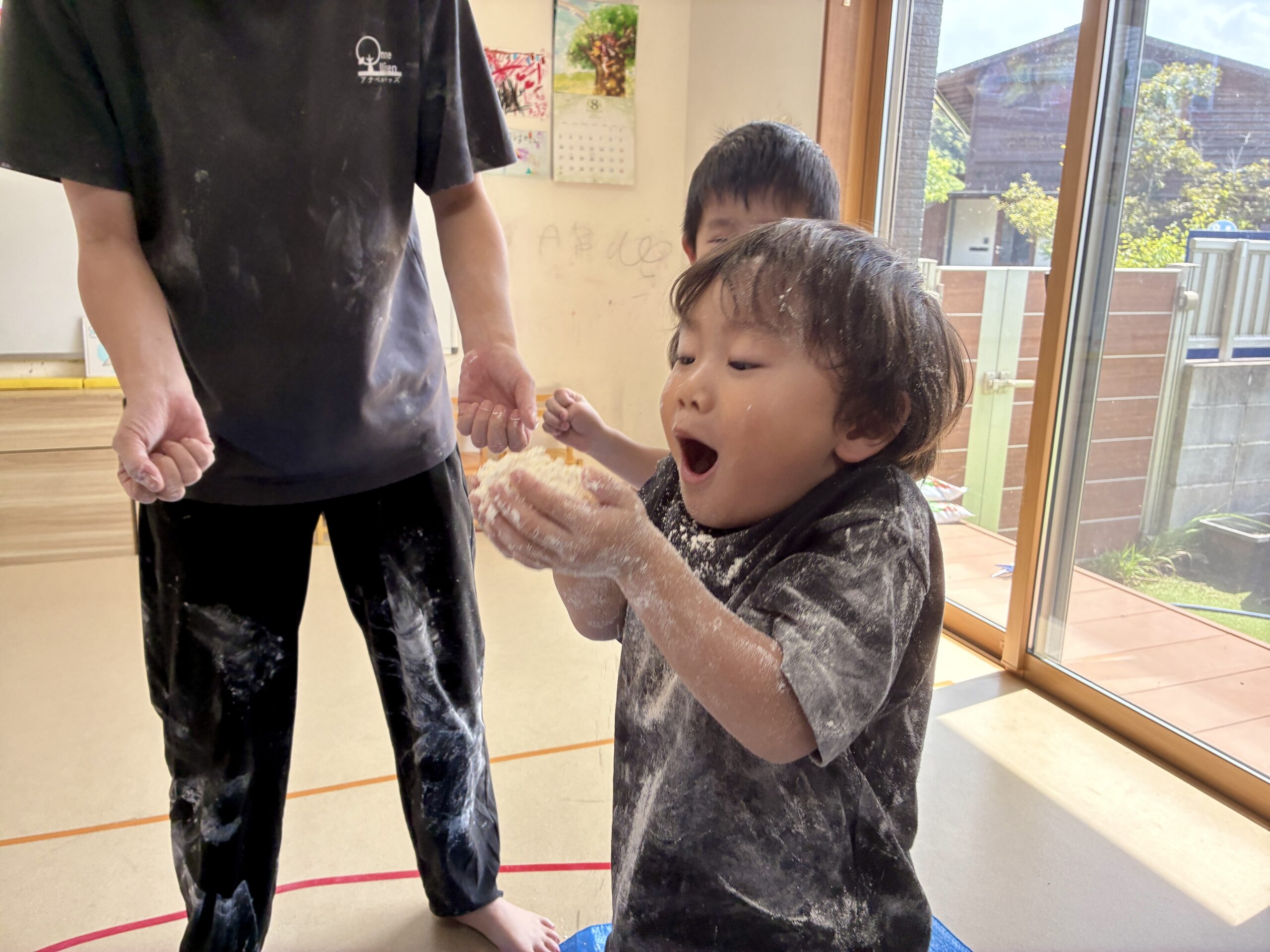 両手の小麦粉に息を吹きかける子