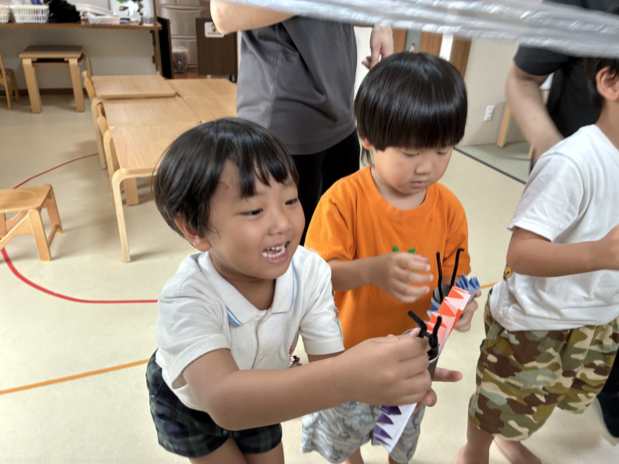 紐に引っかけたコウモリに手を伸ばして笑うこども