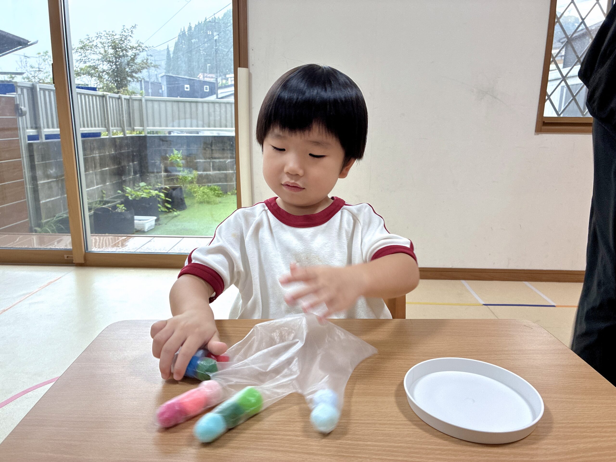ビニール手袋の指にポンポンを入れて手を動かす子ども