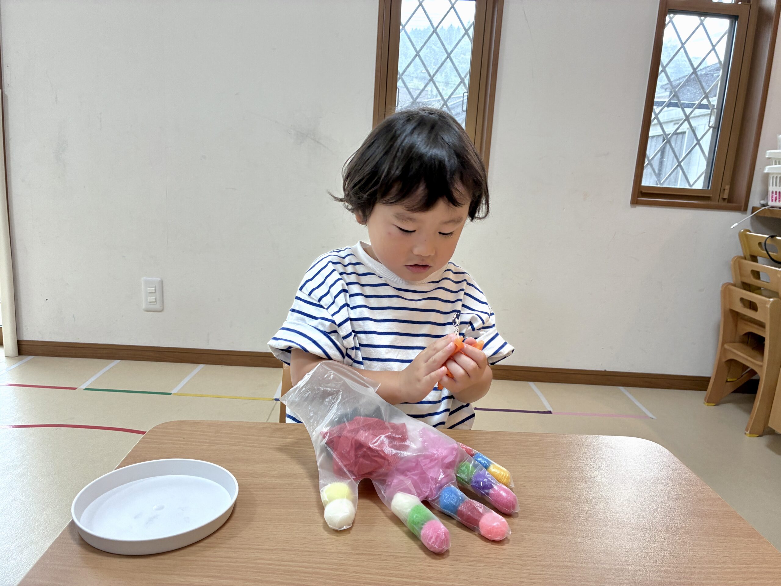 赤い花紙を詰めたビニール手袋でおばけを作る子ども
