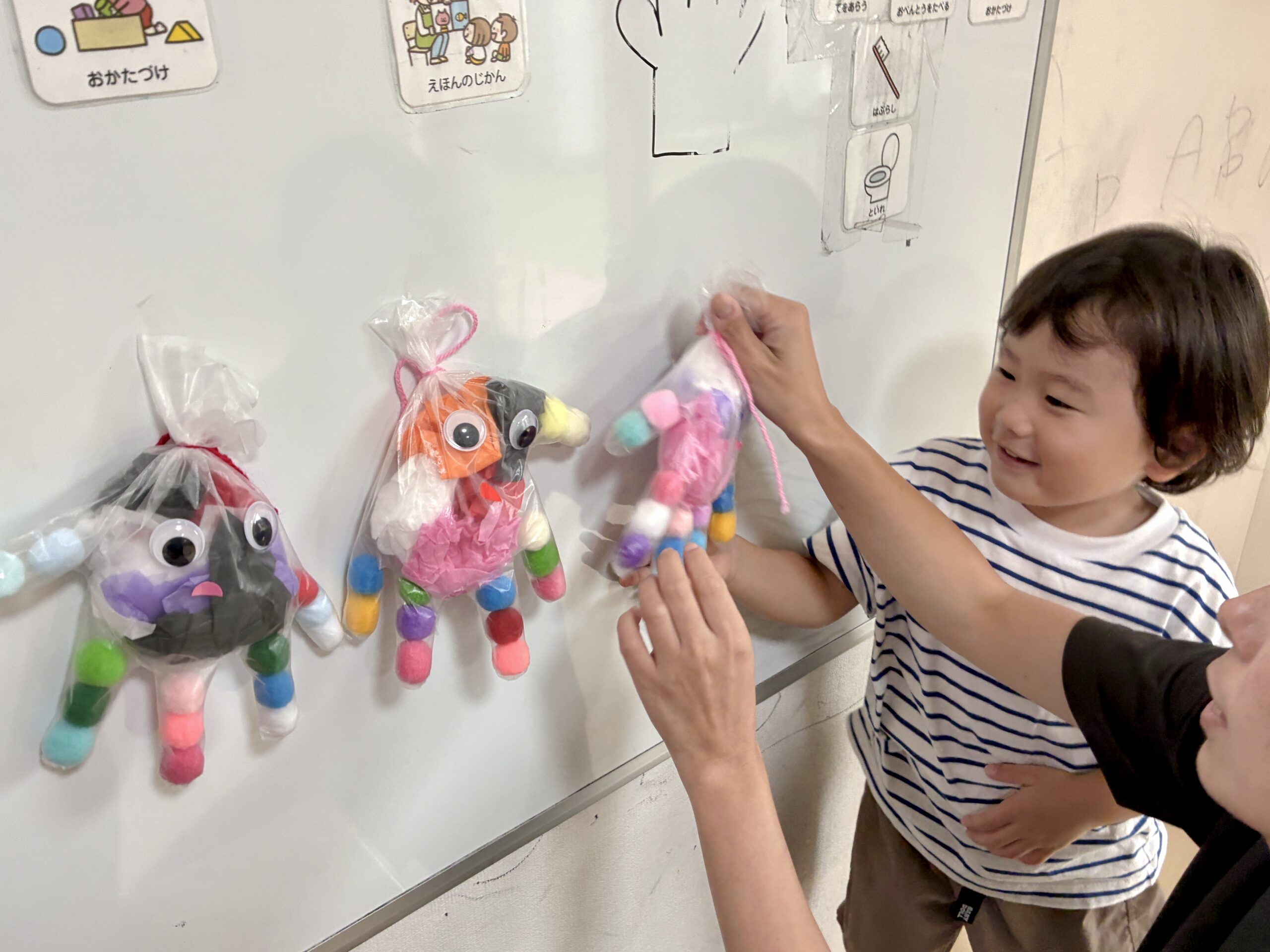 ホワイトボードに並んだ3体のおばけに手を伸ばす子ども