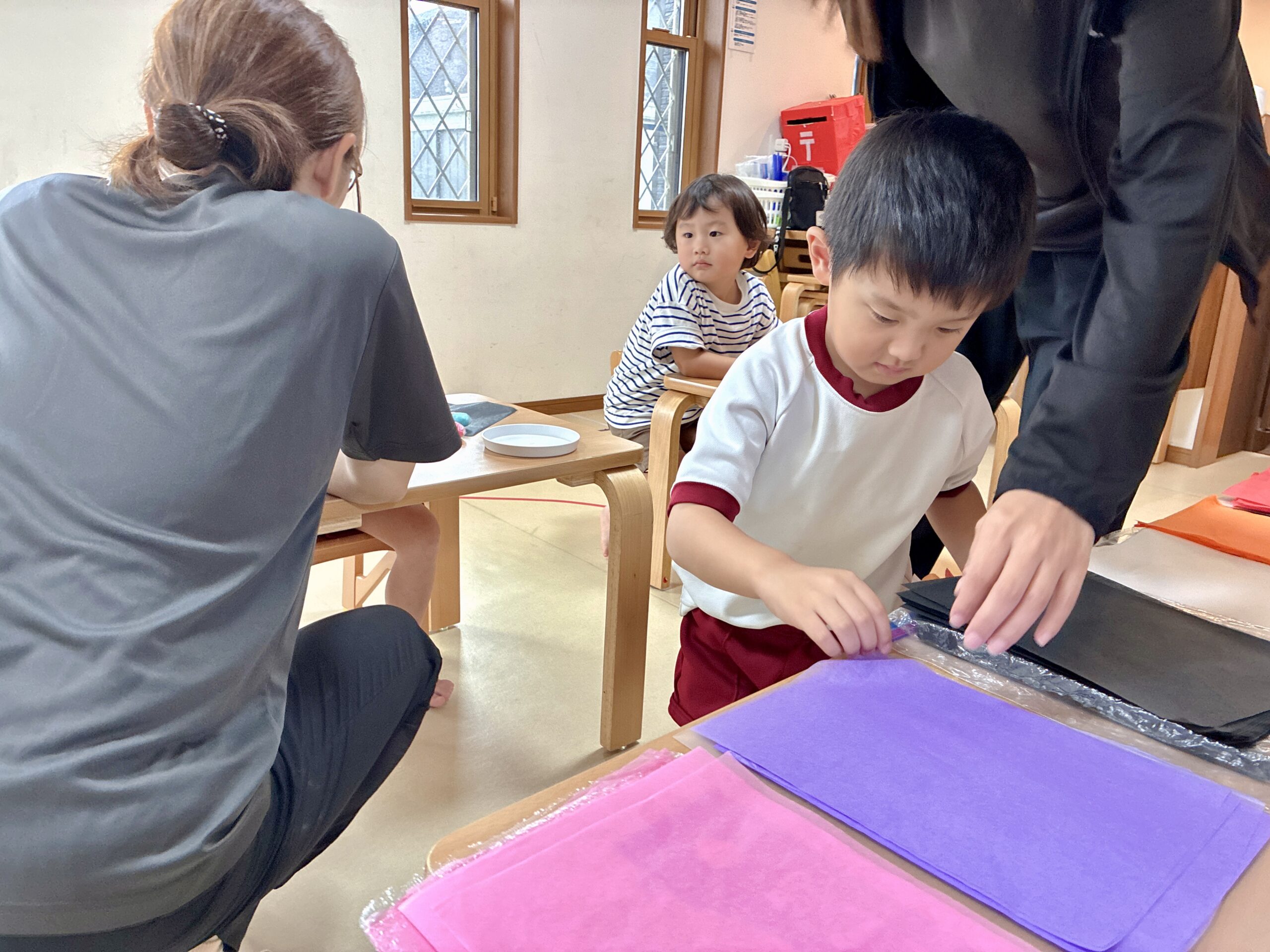 紫とピンクの花紙を選ぶ子どもと職員