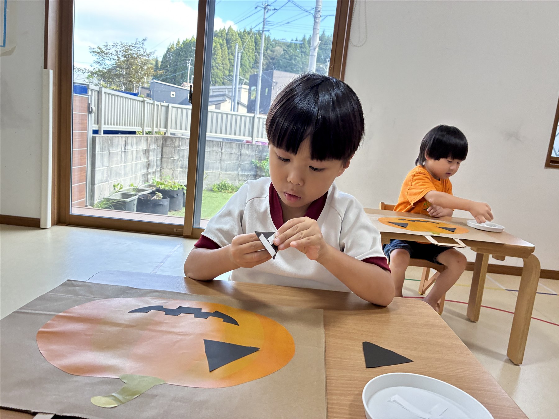 かぼちゃの紙に、目と鼻を貼るこども