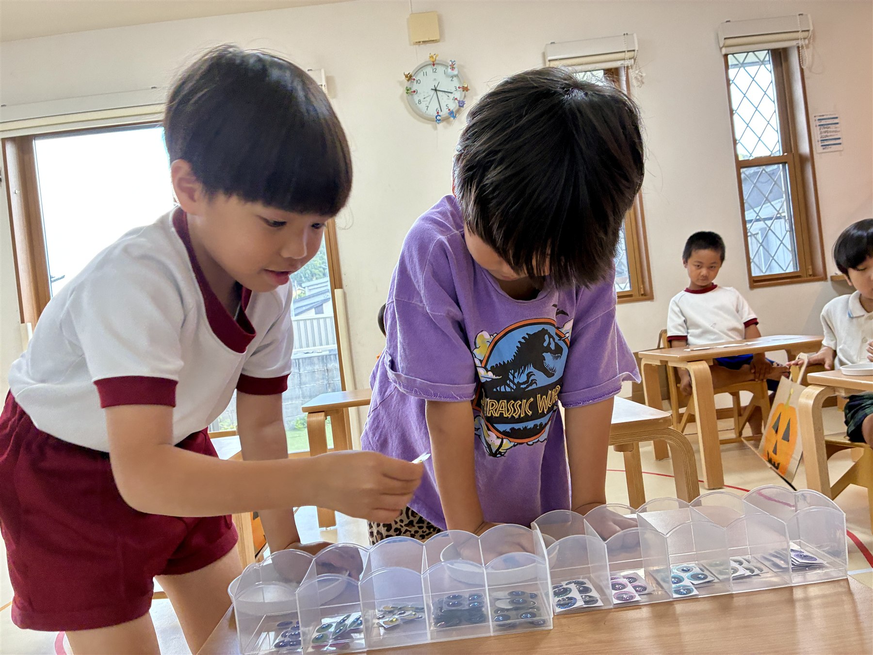 容器から、おばけの目のシールを選ぶこどもたち