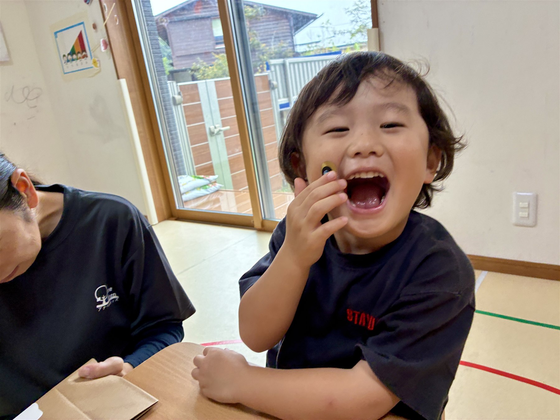 選んだ目のシールを手に、大きな口で笑うこども