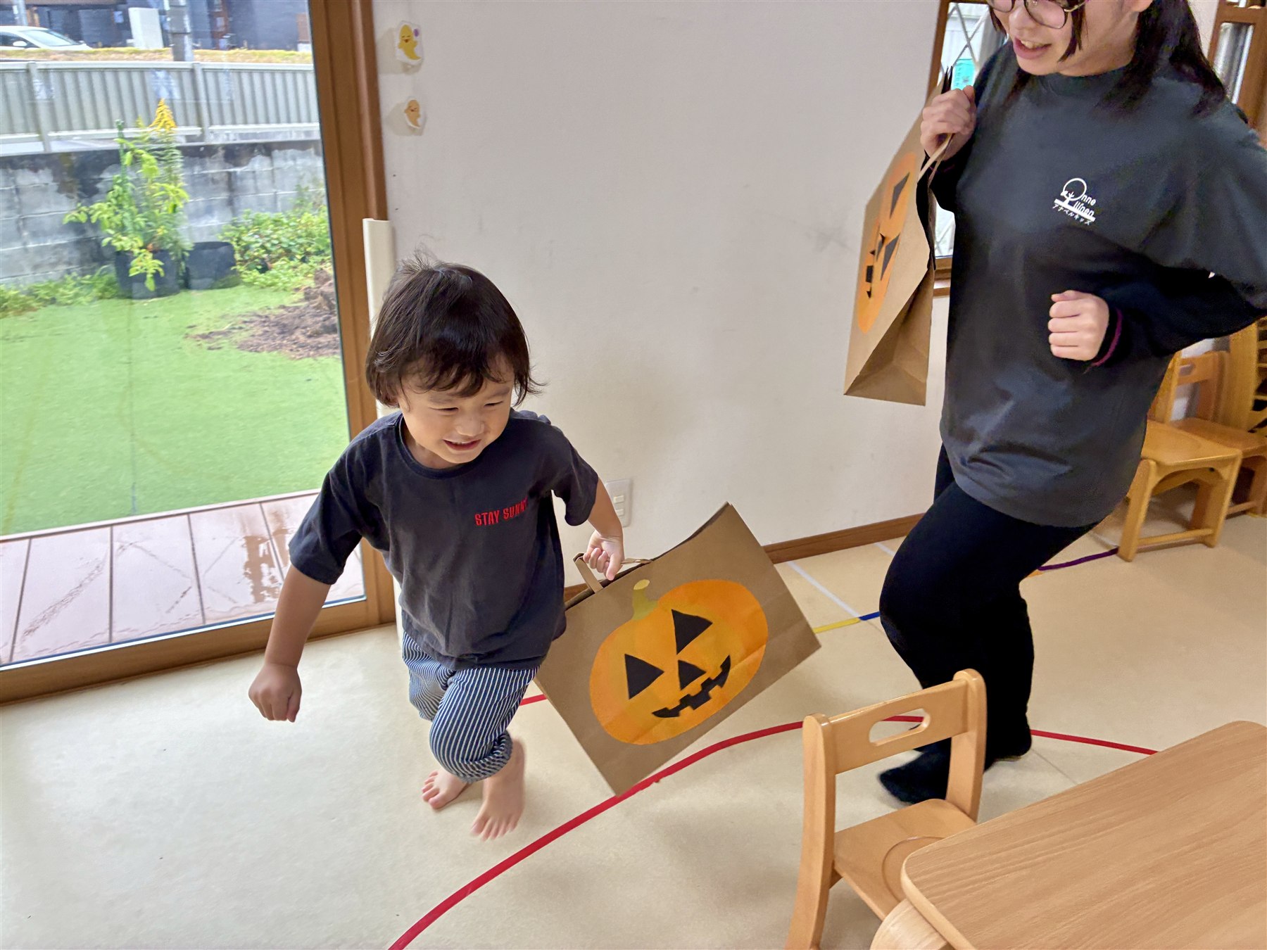 かぼちゃのバッグを手に、元気に歩くこどもとスタッフ