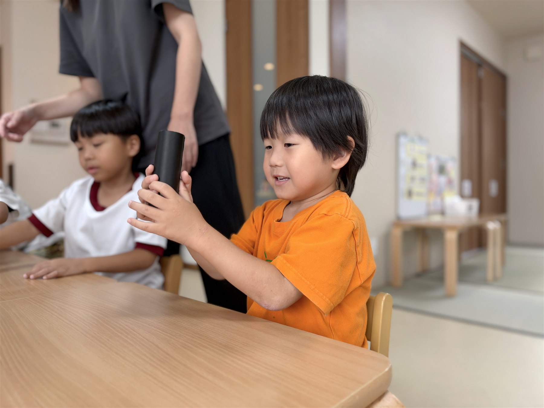 黒い折り紙の筒を両手で持つこども
