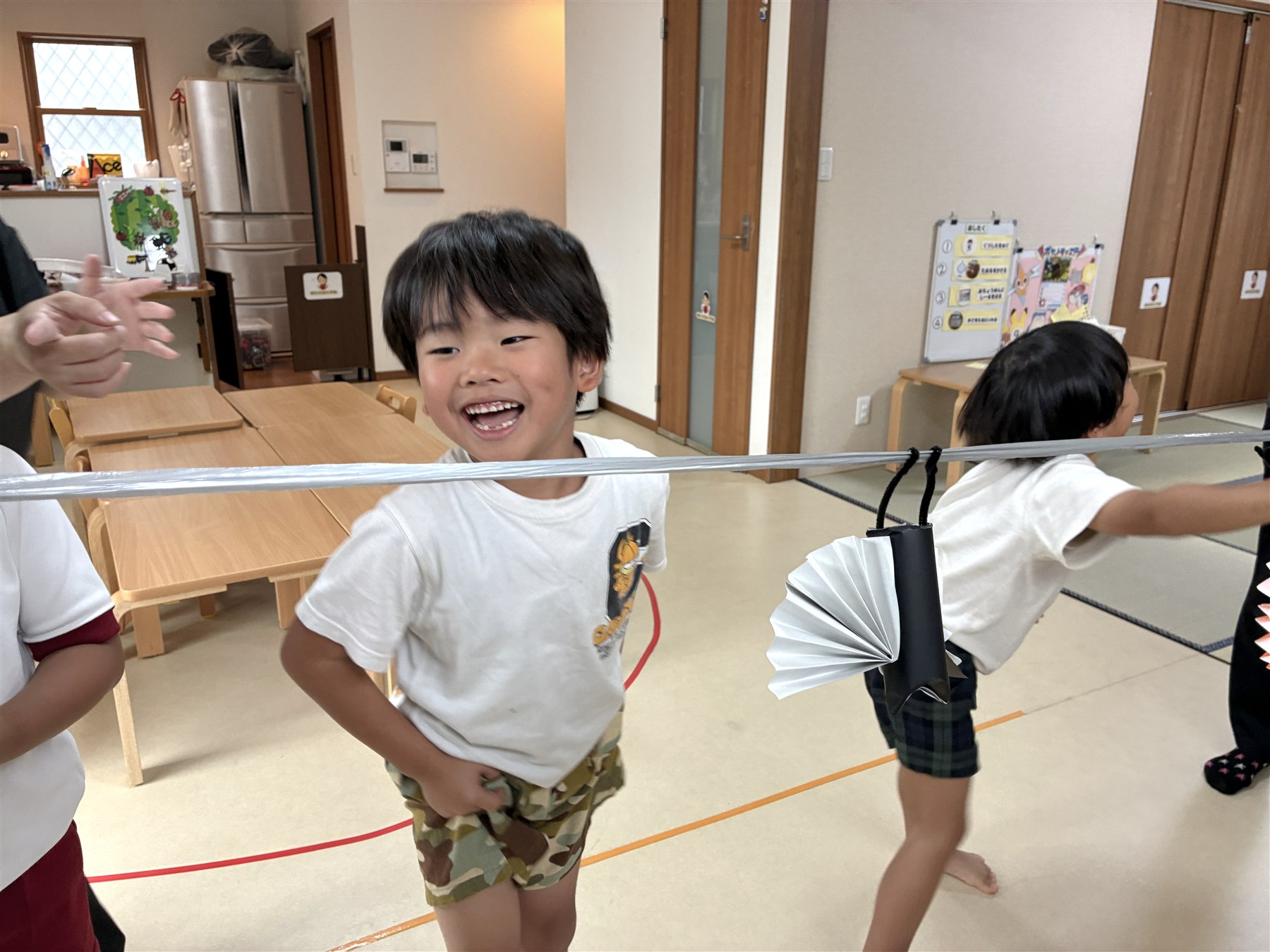 紐の下で笑うこどもと、紐に下がるコウモリ