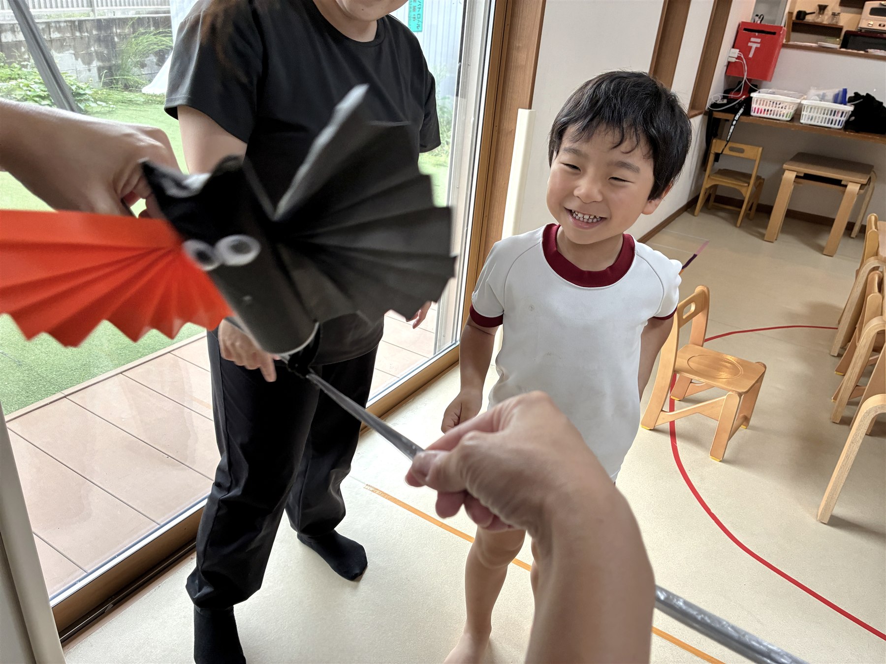 棒の先のコウモリの前で笑顔を見せるこども