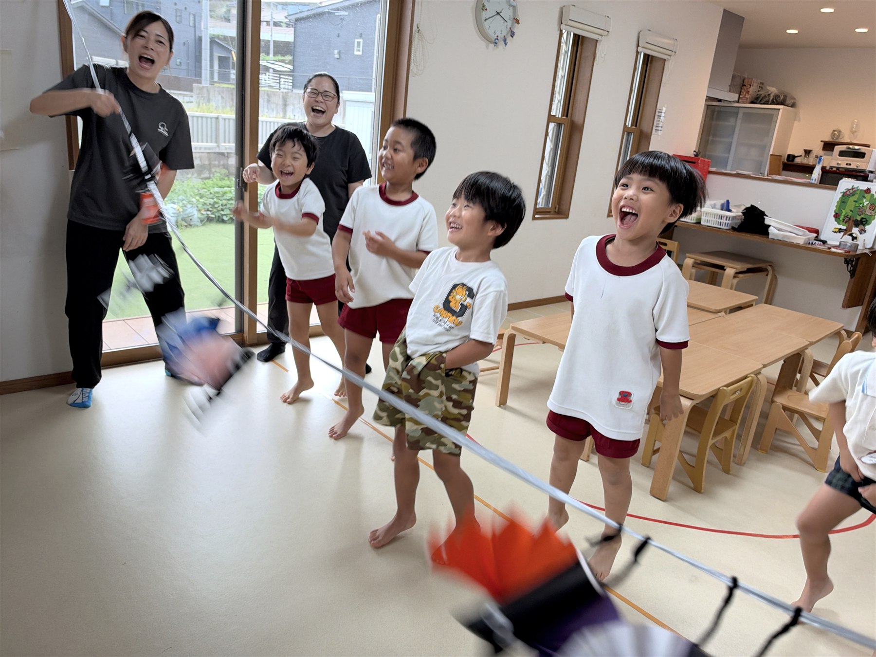 紐に引っかけたコウモリの飾りを揺らして笑うこどもたちとスタッフ