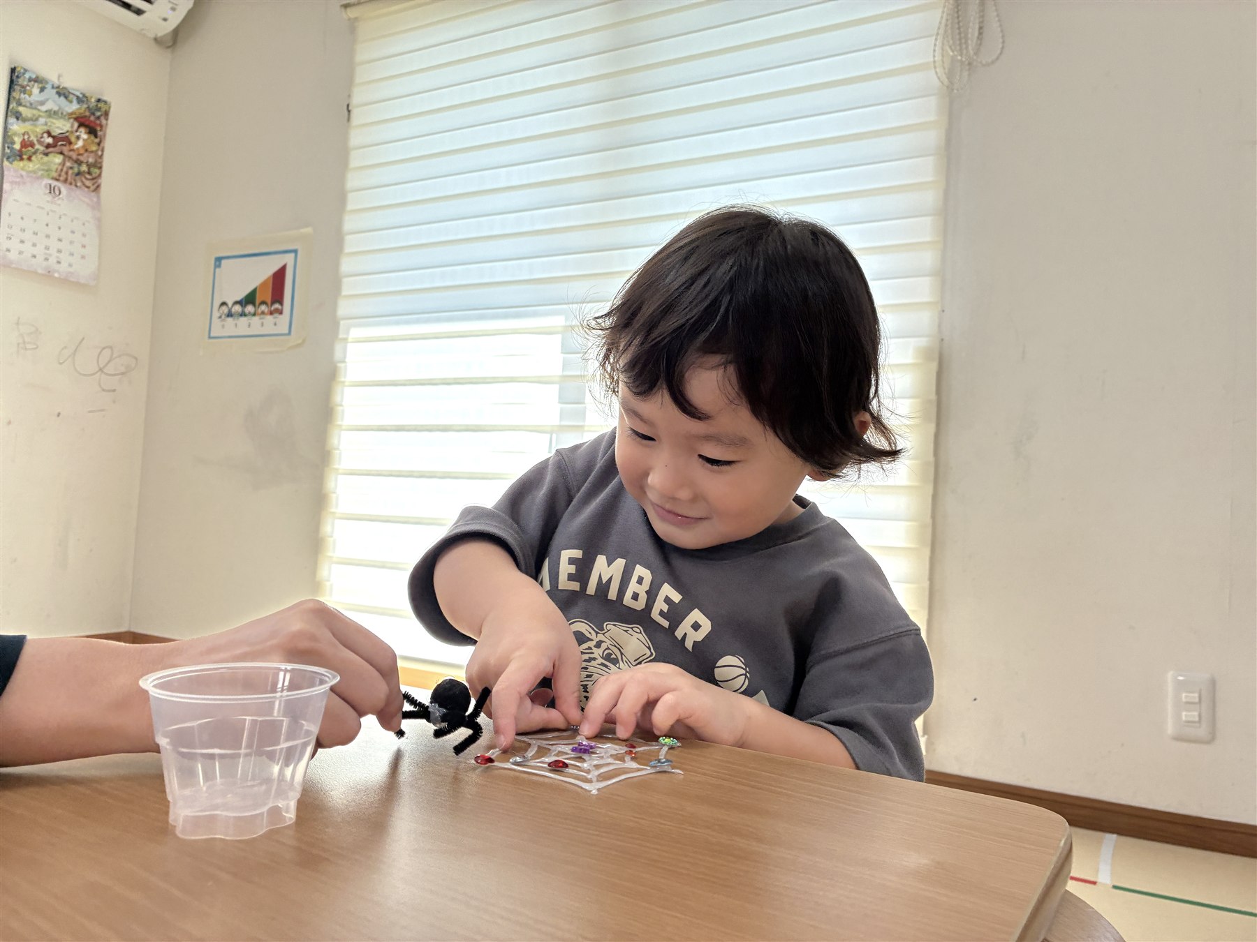蜘蛛の巣にキラキラのシールを貼るこども